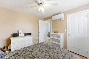 Bedroom with a mini split for heating / cooling, a ceiling fan, and light wood-style floors