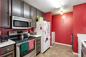 Kitchen with stainless steel appliances, light countertops, and dark wood finish cabinets