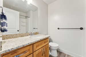 Bathroom featuring vanity, wood finished floors, and a shower