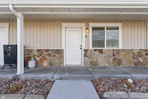 Doorway to property featuring stone siding and covered porch