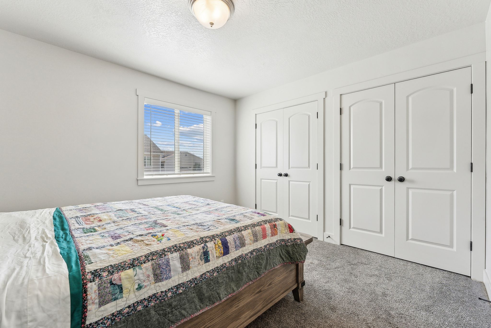 Carpeted bedroom with two closets and a textured ceiling