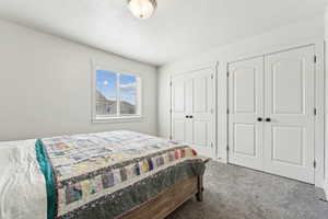 Carpeted bedroom with two closets and a textured ceiling