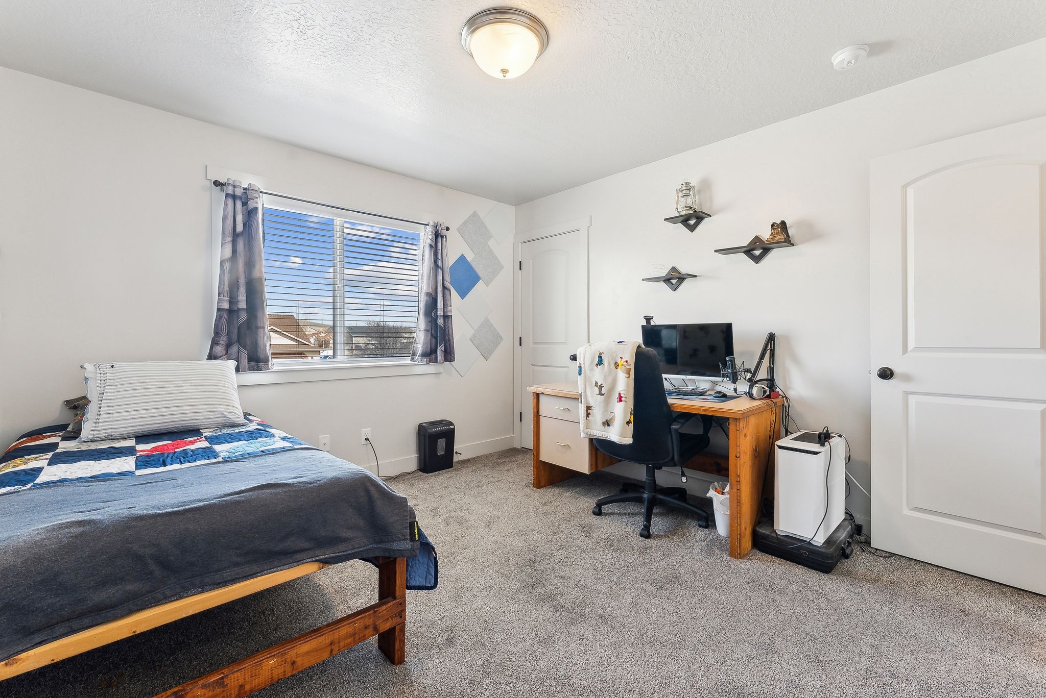 Bedroom featuring light colored carpet, an office area, and a textured ceiling