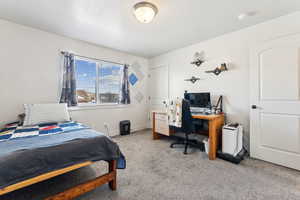 Bedroom featuring light colored carpet, an office area, and a textured ceiling