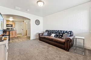 Living area featuring arched walkways, light colored carpet, and an accent wall