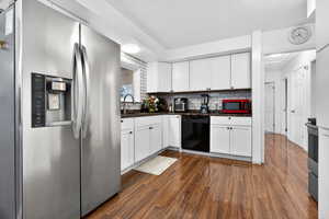 Kitchen with stainless steel refrigerator with ice dispenser, dark wood-style flooring, white cabinetry, dishwasher, and backsplash