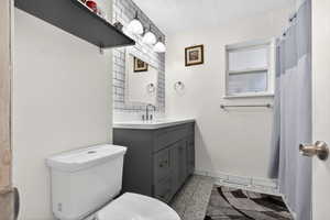 Bathroom with vanity, curtained shower, light tile patterned floors, and a textured ceiling