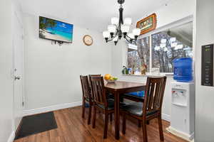 Dining area with dark wood-style floors and suspended lighting