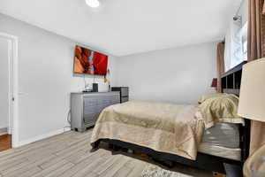 Bedroom featuring fridge and light wood-style floors