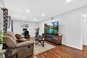 Living room featuring dark wood-type flooring, recessed lighting, and a glass covered fireplace