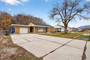 Single story home with a garage, driveway, brick siding, and a mountain view