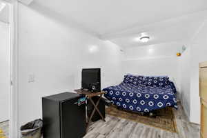Bedroom with black refrigerator and light wood finished floors
