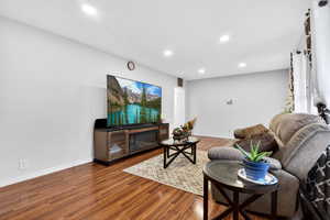 Living room with wood finished floors, recessed lighting, and a glass covered fireplace