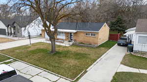 Ranch-style house featuring concrete driveway, brick siding, a front yard, and roof with shingles