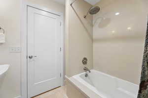 Full bath featuring shower / bathtub combination with curtain and light tile patterned floors