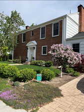 Colonial home featuring a chimney and brick siding