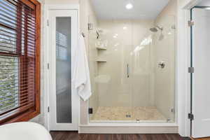Full bath with a stall shower and dark wood finished floors