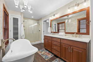 Bathroom featuring a chandelier, double vanity, a soaking tub, and a stall shower