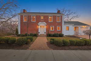 Colonial-style house with a chimney and brick siding