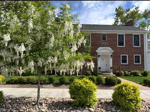 View of front of home with brick siding and a chimney