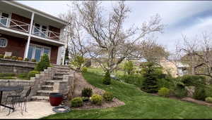 View of grassy yard featuring a patio and a balcony