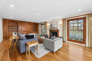 Living area featuring built in shelves, recessed lighting, a premium fireplace, and light wood-type flooring