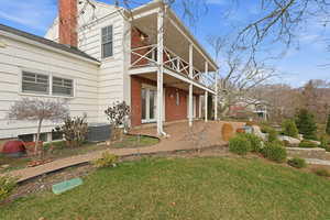 View of front facade with a patio area, a chimney, a front yard, french doors, and a balcony