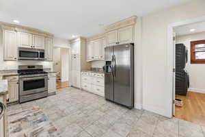 Kitchen featuring stainless steel appliances, cream cabinetry, light stone countertops, recessed lighting, and light tile patterned floors