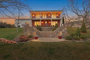 Rear view of property with a lawn, a patio, and brick siding