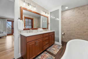 Bathroom featuring a freestanding bath, dark wood-style floors, and double vanity