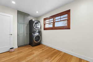 Laundry area featuring stacked washer / drying machine, light wood-style floors, and recessed lighting
