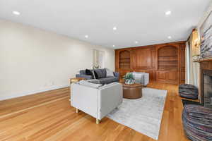 Living room featuring built in shelves, recessed lighting, a fireplace, and light wood-style flooring