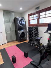 Exercise room featuring stacked washer / dryer and light wood-style flooring