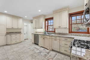 Kitchen featuring cream cabinetry, stainless steel appliances, recessed lighting, and light stone counters