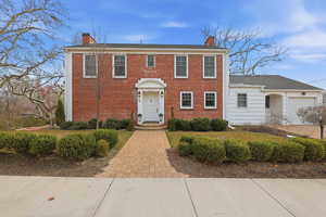 Colonial home featuring a chimney and brick siding