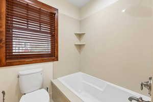 Bathroom featuring toilet and a tub to relax in
