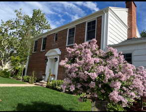 Colonial house with a chimney, a front lawn, and brick siding