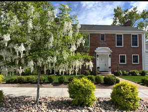 View of front of house featuring a chimney and brick siding