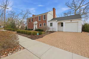 Colonial inspired home with a chimney, a garage, and decorative driveway