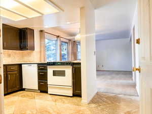 Kitchen with white appliances, light stone counters, light colored carpet, backsplash, and pendant lighting