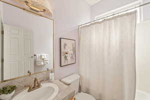 Bathroom featuring a shower with shower curtain, vanity, and tasteful backsplash