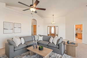 Living room with light carpet, vaulted ceiling, ceiling fan, and arched walkways