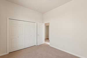 Unfurnished bedroom with light colored carpet and a closet
