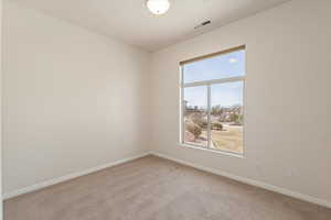 Empty room featuring light colored carpet and baseboards