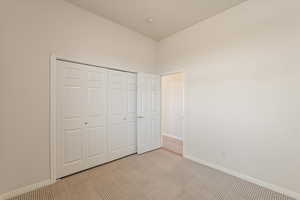 Unfurnished bedroom featuring light colored carpet and a closet