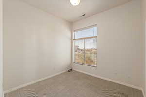 Unfurnished room featuring light carpet and baseboards