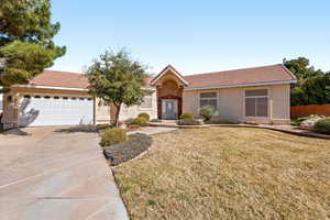 Single story home featuring an attached garage, a front lawn, a tile roof, and driveway