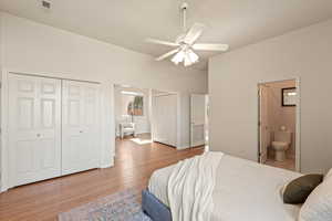 Bedroom featuring two closets, connected bathroom, light wood-type flooring, and ceiling fan