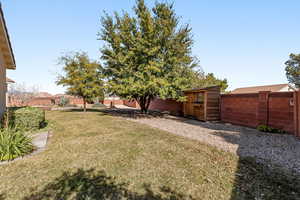 Fenced backyard featuring a shed