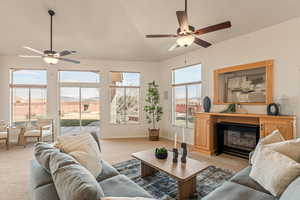 Living room featuring ceiling fan, a glass covered fireplace, and light carpet